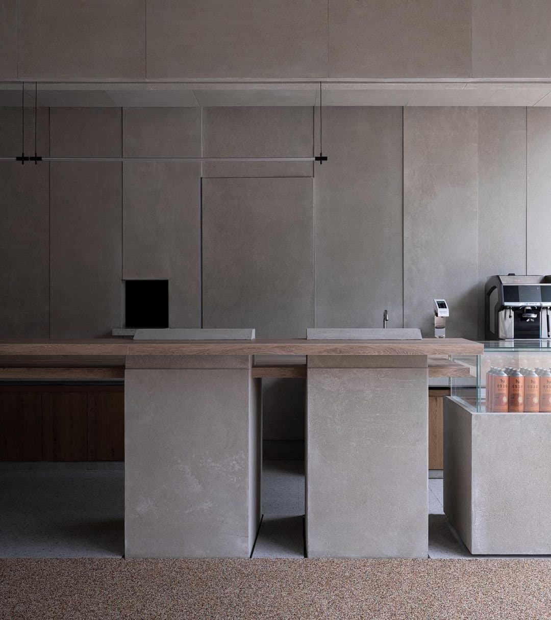 The tank displays flank the bar, both embedded within a sweeping C-shaped concrete beam that spans across the space. Here, t...